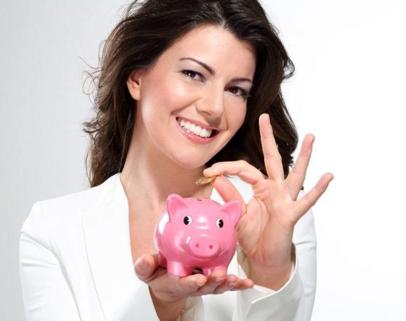 Young beautiful woman standing with piggy bank money box on white